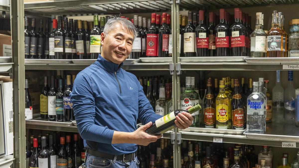 AGCO employee holding a wine bottle in a liquor store.